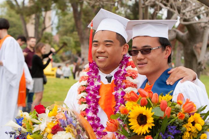 2015年毕业典礼，两个亚洲男人拿着花